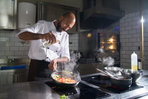 Chef cooking in commercial kitchen on electric stovetop