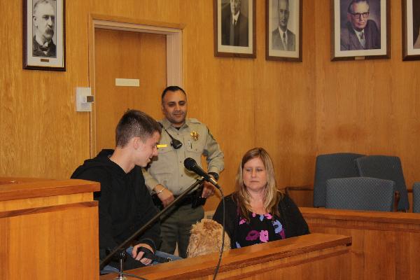 A man and woman stand in court with a dog